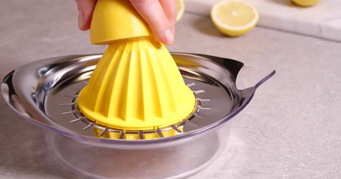 Woman squeezing lemon juice with reamer at table, closeup
