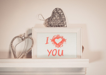 Valentines message on a small chalkboard with heart shaped hangers.
