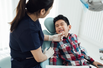 Female dentist examining kids teeth in dentist's office