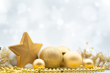 A design of festive gold Christmas decorations under a wintry white bokeh background with copy space