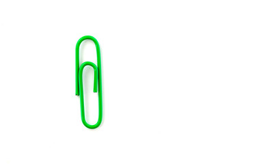 Green paper clip isolated on white background. Close up and top view.