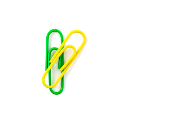 Green and yellow paper clip isolated on white background. Close up and top view.
