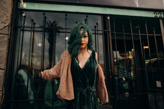 Young retro model hanging outside of a closed store leaning off of the bars on the sidewalk outside