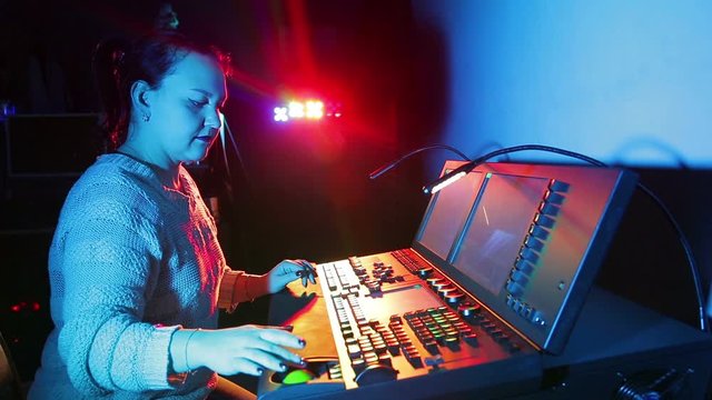 The female illuminator sets up the mixing light console and saves the programs