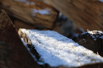 Firewood stacked in winter. Wood pile with snow stacked for firewood. Chopped stock of firewood under snow. Piles of snow covered firewood at cold winter day