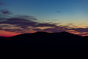 atmospheric natural wallpaper poster photography of mountain silhouette on cloudy twilight sky background after sunset, empty copy space