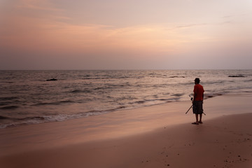 Fototapeta na wymiar Susnet at Anjuna beach goa with a man on the beach