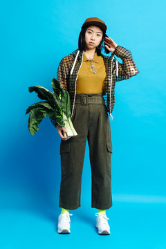 Young serious stylish lady in cap with bunch of plants