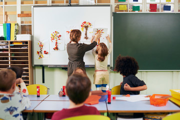 Teacher and her pupil hanging paper art work