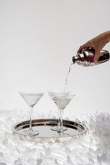 Pouring alcohol into martini glass on white background