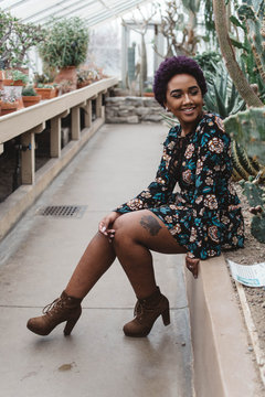 A beautiful young black woman with a purple afro in a tropical setting
