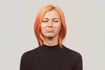 Worried woman closing her eyes cries in depression looking sick and tired of work. Young beautiful...