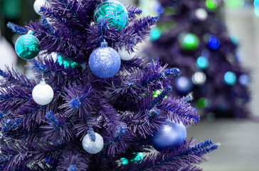 Obraz na płótnie Canvas Decorated blue christmas tree with reflection of sparkling second christmas tree. Bright blue Christmas wallpaper with two elegant conifers, one out of focus. Wallpaper, congratulation, 2020, new year