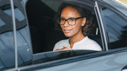 Beautiful businesswoman sitting on back seat of a car 
