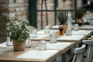 beautifully laid tables with glasses and appliances at night in restauran with blur background