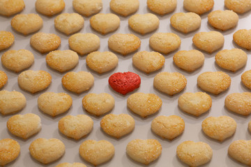 Many identical cookies on the table, one cookie is differentю One red cookie among many identical. Leadership, uniqueness, thinking differently, team success in business