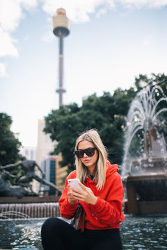 Pretty young lady with sunglasses using phone in Sydney.