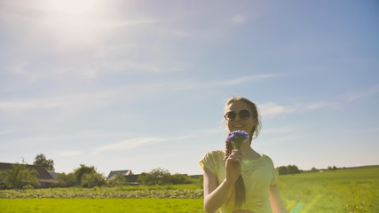 Young 17 year old girl with a cornflower flower outside the city on a summer day.