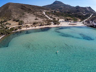Plathiena beach with man swimming, mountains and vegetation