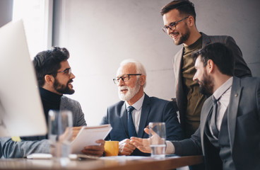 Three young employees soaking in vast experience shared by a senior manager in an office.