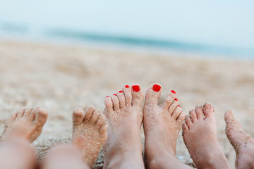 Female foot and foot of two children on sea background.