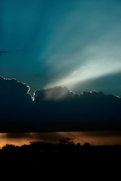 Sunbeams behind dark clouds in sky