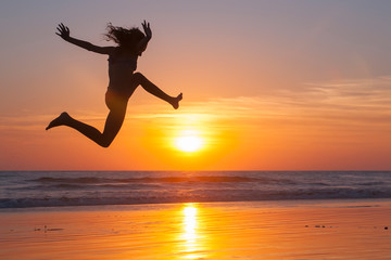 girl jumping on the beach at sunset