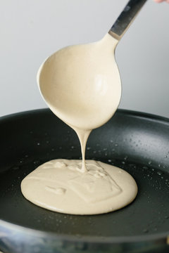 Ladle of vegan pancake batter being poured into a pan