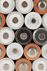 Pile of old white, black and golden AA batteries showing positive end