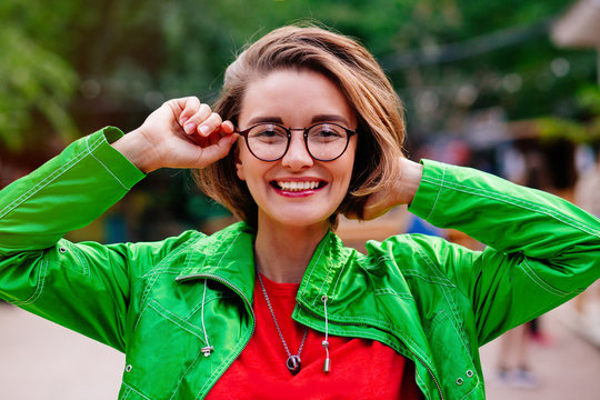 Close-up portrait of beautiful caucasian woman with charming smile walking outdoors.Close up portrait of a beautiful smiling girl with brown hair wearing glasses and looking at camera outdoors