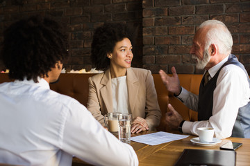 Three businesspeople at the table discussing a business deal in an interesting indoor establishment.