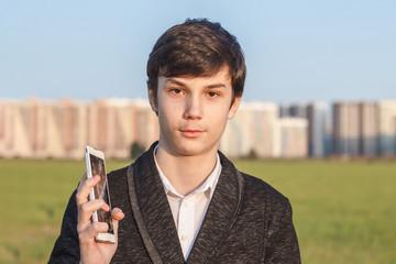 Portrait of handsome teen boy holding broken phone shows emotion of ambiguity