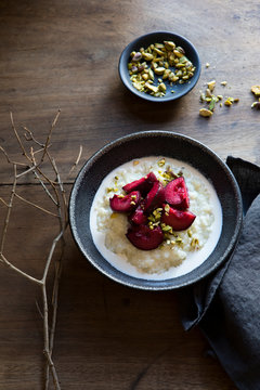Rice pudding with roasted red plums, cream and pistachio nuts
