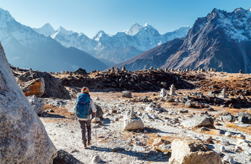 Young female backpacker following Everest Base Camp trekking route using trekking poles and enjoying valley view with Ama Dablam peak. She came to Everest Memorial to lost Mountaineers (4800m)