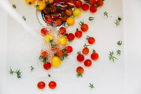 little tomatoes being washed in a sink