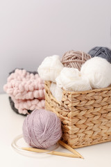 Fototapeta na wymiar Wooden knitting needles and balls of yarn in wicker basket on light background. Concept of hobby. Handicraft