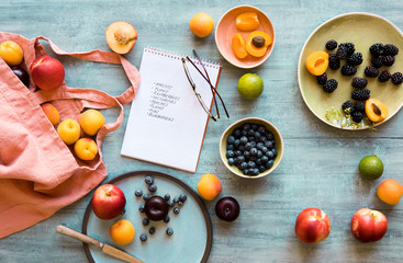 Shopping bag, shopping list and fresh fruits on blue tabletop