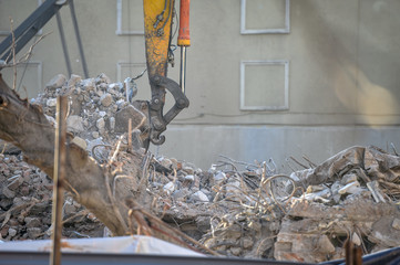Site of a demolished building with an excavator carrying out the debris