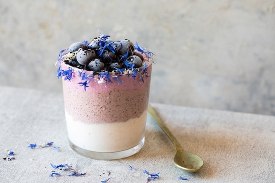 Breakfast smoothie topped with berries, acai berry powder, toast