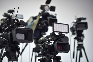 Several video cameras broadcasting at press conference.