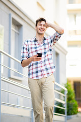 Fototapeta premium happy young guy walking with cellphone outside