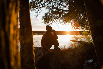 Woman Sitting on Rock at Sunset with a Drink