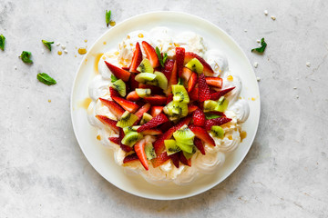Pavlova dessert with strawberries, kiwi fruit and cream