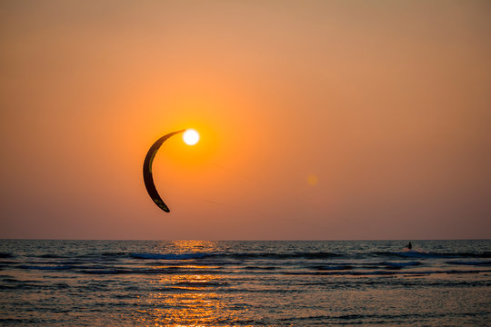 Kitesurfer touches the sun at sunset