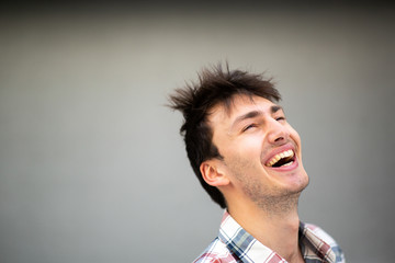 Fototapeta premium Close up portrait handsome young man laughing by gray background