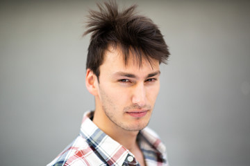 Close up portrait handsome young man with serious expression by gray background