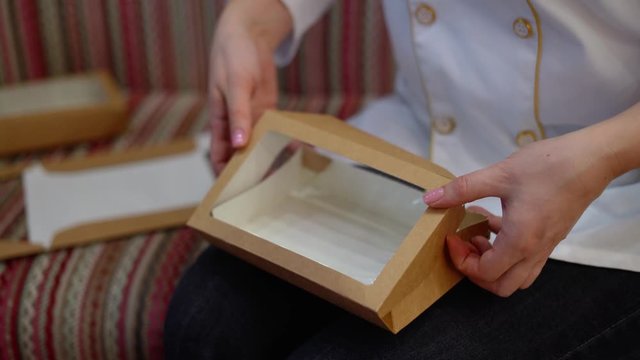 Hand is folding paper box. The cook is folding a gift box on his lap-2.