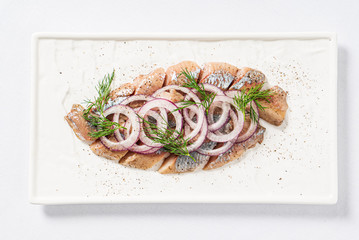 herring with red onion on the white plate