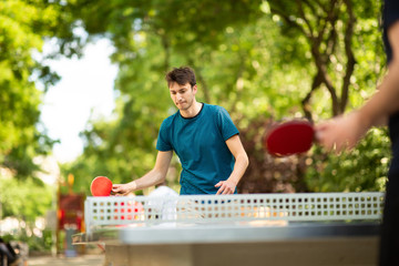 young man playing table tennis in park - obrazy, fototapety, plakaty