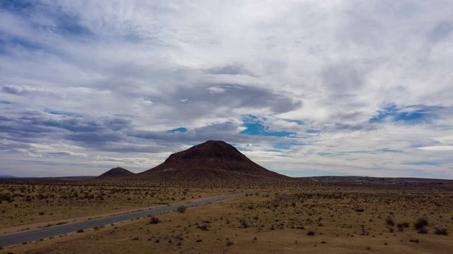 Hyperlapse moving toward Mojave Desert rock hill on cloudy day